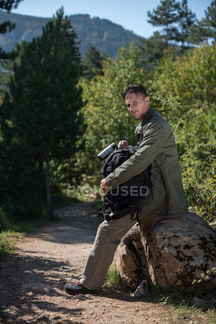 Caminhante sentado em uma rocha segurando sua mochila, Bósnia e Herzegovina — Fotografia de Stock
