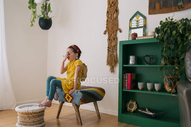 Дівчина сидить на табуреті з рукою на голові — стокове фото