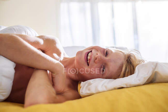 Sonriente niño acostado en la cama riendo - foto de stock