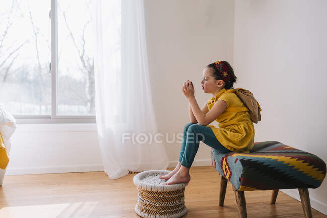 Mädchen sitzt auf einem Schemel und betrachtet ein Blatt Papier — Stockfoto
