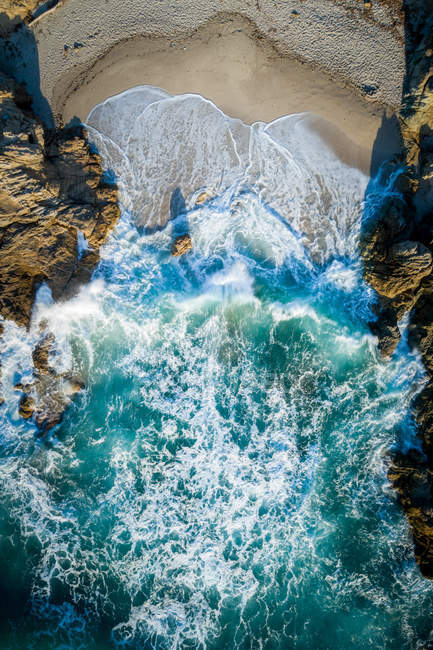 Vue aérienne de l'eau bleue de l'océan écrasant sur les rochers sur la plage — Photo de stock