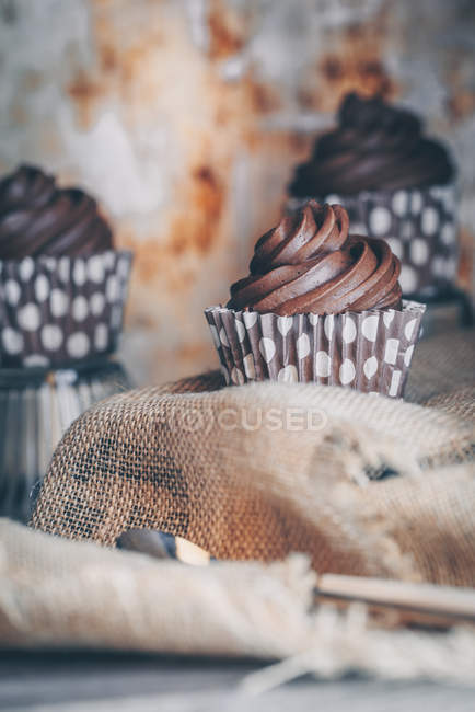 Tres cupcakes de chocolate en una mesa de madera - foto de stock