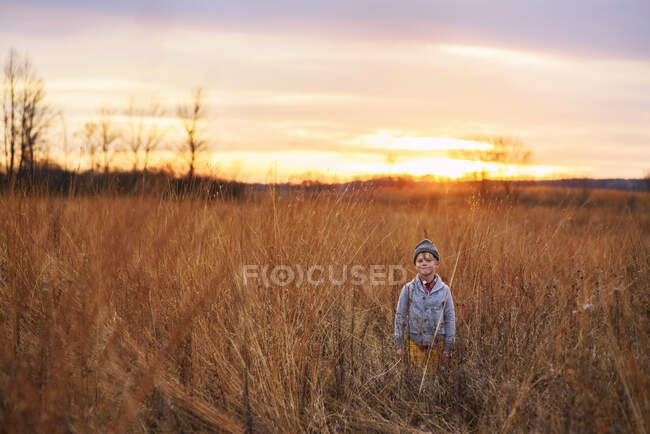 Хлопчик, що стоїть на полі на заході сонця (США). — стокове фото