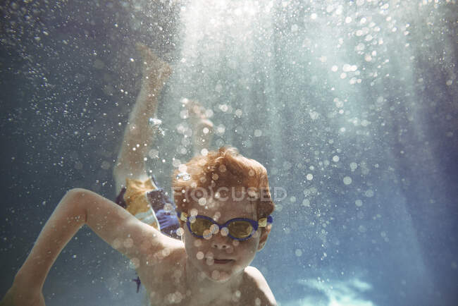 Крупный план мальчика, плавающего под водой в бассейне — стоковое фото