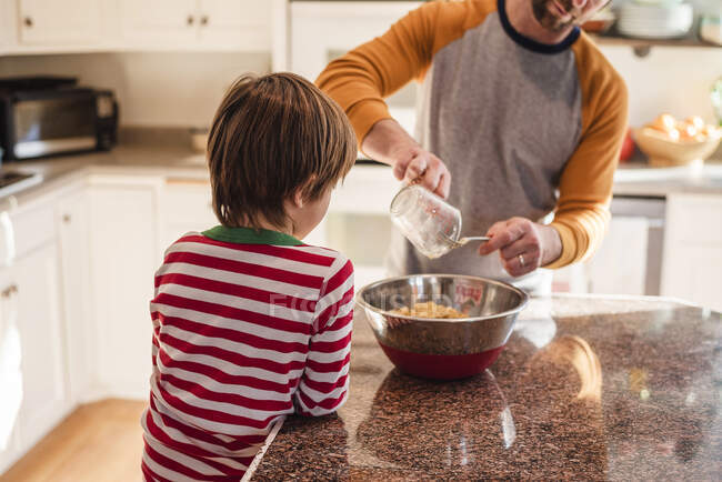 Мальчик помогает отцу печь на кухне. — стоковое фото
