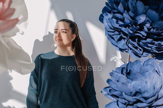 Portrait of a woman standing next to giant artificial flowers — Stock Photo