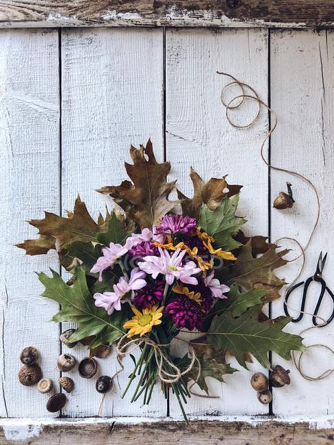 Buquê de outono de flores em uma mesa de madeira com bolotas e tesouras — Fotografia de Stock