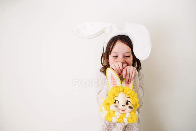 Retrato de uma menina sorridente usando orelhas de coelho segurando um saco de coelho — Fotografia de Stock