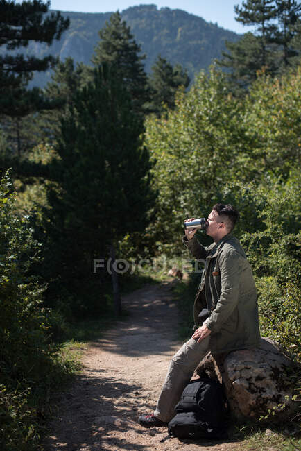 Wanderer sitzt auf einem Felsen und trinkt Wasser, Bosnien und Herzegowina — Stockfoto