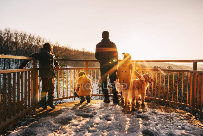 Padre, tres hijos y un perro mirando a la vista, Estados Unidos - foto de stock