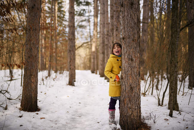Chica sonriente escondida detrás de un árbol, Estados Unidos - foto de stock