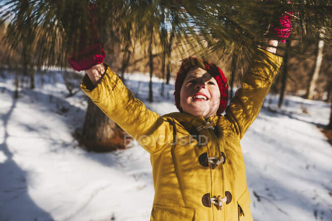 Menina de pé na floresta, chegando a um ramo de árvore no inverno, Estados Unidos — Fotografia de Stock