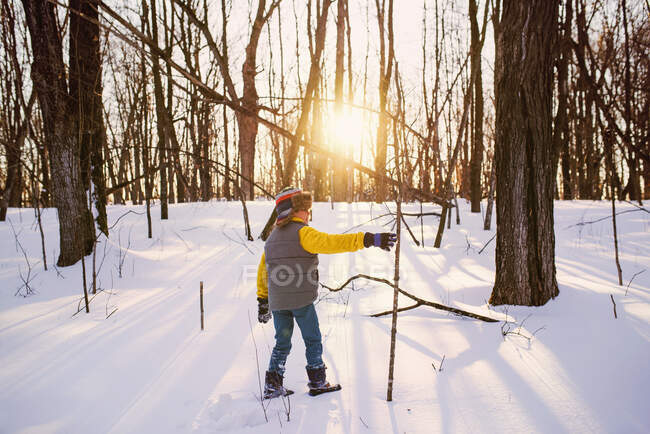 Boy senderismo a través del bosque en la nieve, Estados Unidos - foto de stock