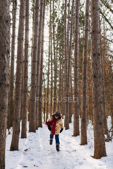 Chico corriendo por el bosque en la nieve, Estados Unidos - foto de stock