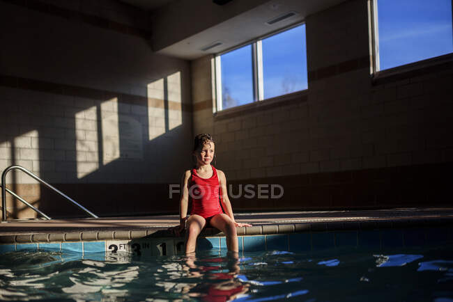 Menina sentada na beira de uma piscina — Fotografia de Stock