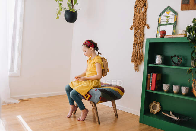 Ritratto di una ragazza seduta su uno sgabello che guarda un pezzo di carta — Foto stock