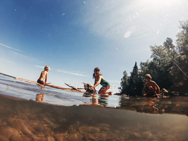 Three children sailing on a lake on a wooden raft, Lake Superior, United States — Stock Photo