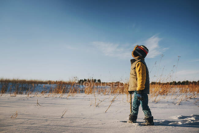 Boy walking through a field in the snow, Estados Unidos — Fotografia de Stock