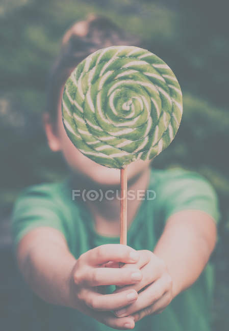 Boy holding a giant lollipop in front of his face — Stock Photo