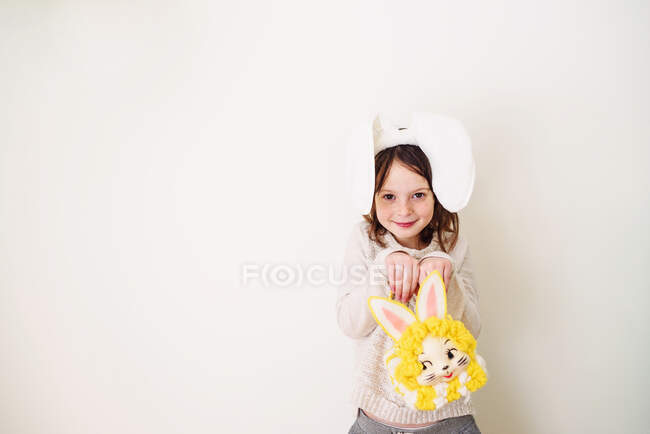 Ritratto di una ragazza sorridente che indossa orecchie da coniglio con in mano una borsa da coniglio — Foto stock