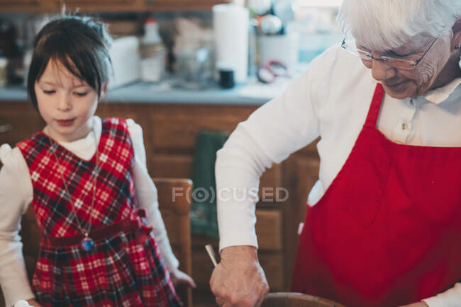 Abuela enseñando a su nieta a hornear - foto de stock