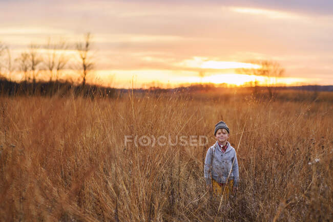 Хлопчик, що стоїть на полі на заході сонця (США). — стокове фото