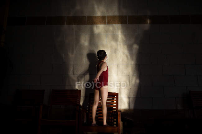 Menina em um traje de natação fazendo sombras contra uma parede — Fotografia de Stock