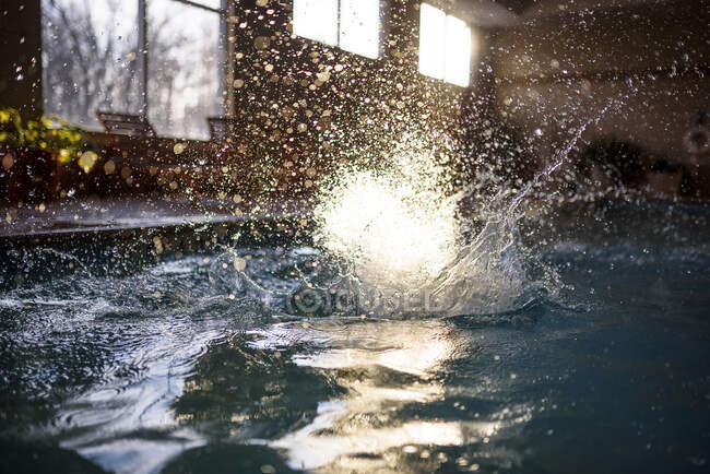 Salpicaduras de agua en una piscina después de que una persona salta en - foto de stock