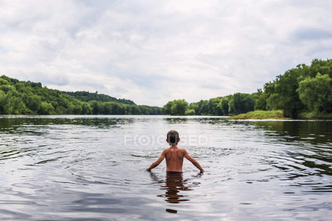 Rear view of a boy standing in a lake, United States — Stock Photo