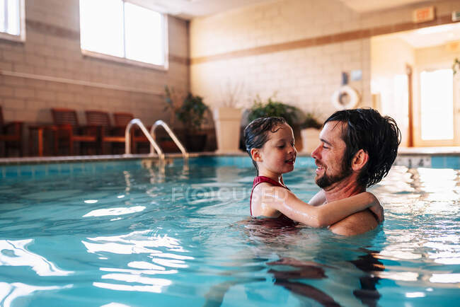 Отец держит свою дочь в бассейне — стоковое фото