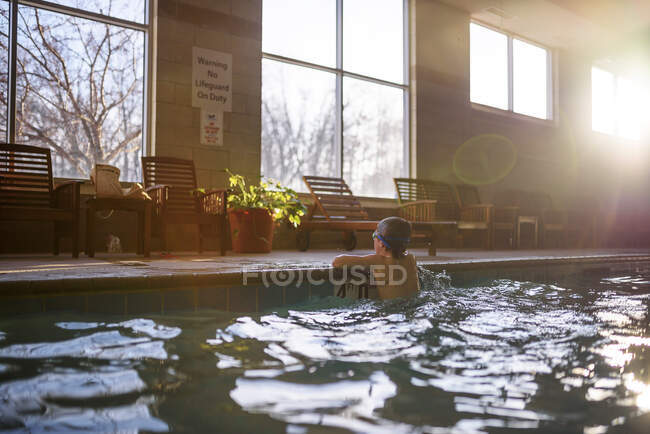 Menino inclinado na borda de uma piscina — Fotografia de Stock