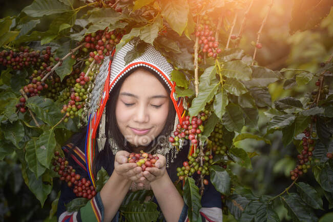 Porträt einer lächelnden Frau mit rohen Kaffeebohnen, Thailand — Stockfoto