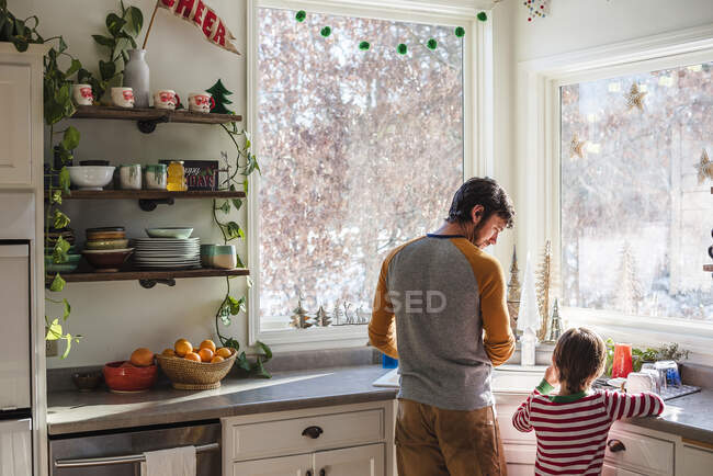 Отец и сын стоят на кухне и моют посуду. — стоковое фото