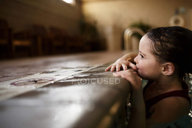 Girl holding on to the edge of a swimming pool — Stock Photo