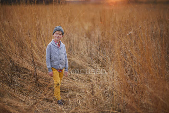 Smiling boy with dirty trousers standing in a field, United States — Stock Photo