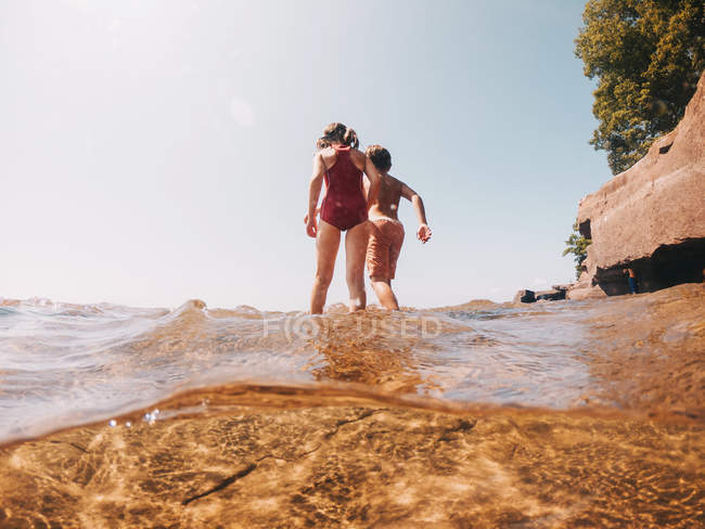 Niño y niña caminando en un lago, Lake Superior, Estados Unidos - foto de stock