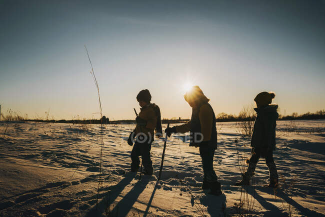 Silueta de tres niños caminando por la nieve, Estados Unidos - foto de stock