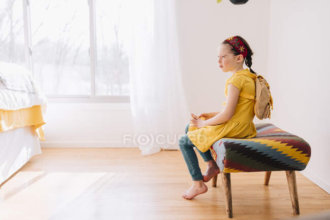 Portrait of a girl sitting on a stool holding a golden gift certificate — Stock Photo