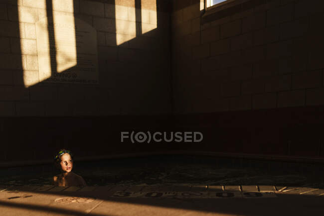 Хлопчик плаває в басейні в тіні — стокове фото