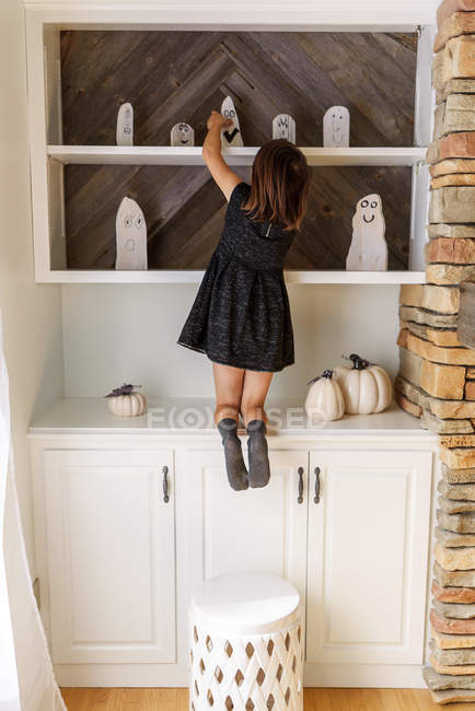 Girl putting up Halloween ghost decorations — Stock Photo