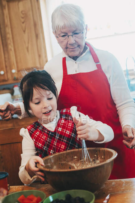 Grand-mère enseignant à sa petite-fille à cuisiner — Photo de stock