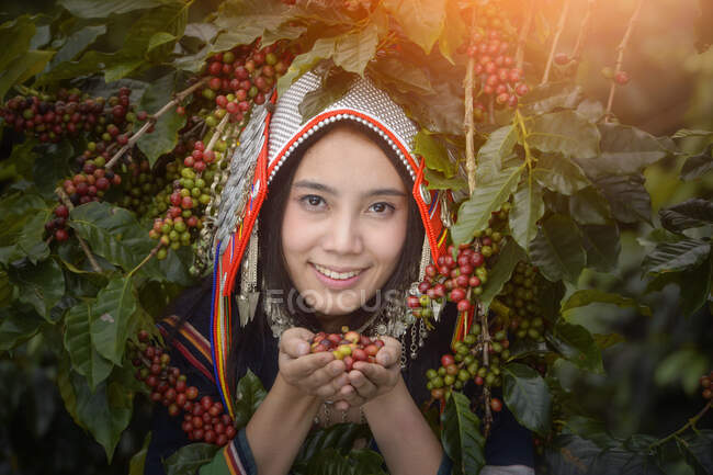 Ritratto di una donna sorridente che tiene in mano chicchi di caffè crudi, Thailandia — Foto stock
