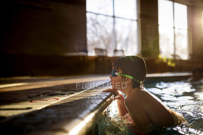 Boy holding on to the edge of a swimming pool — Stock Photo