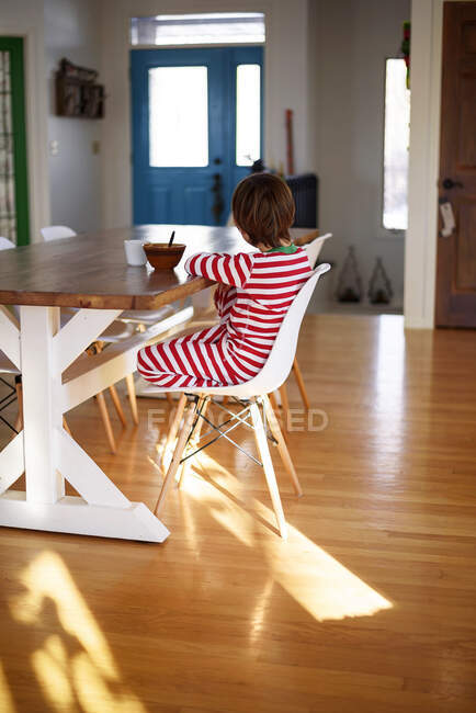 Menino sentado à mesa tomando café da manhã — Fotografia de Stock