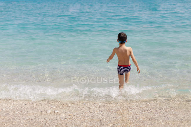 Visão traseira do menino andando no mar, Grécia — Fotografia de Stock
