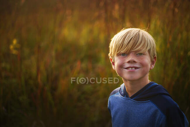 Retrato de um menino sorridente em pé em um campo ao pôr-do-sol, Estados Unidos — Fotografia de Stock