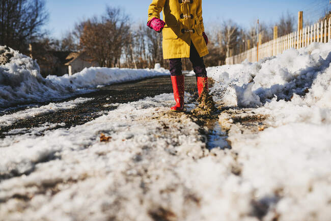Mädchen steht in einer Pfütze aus schmelzendem Schnee, Vereinigte Staaten — Stockfoto