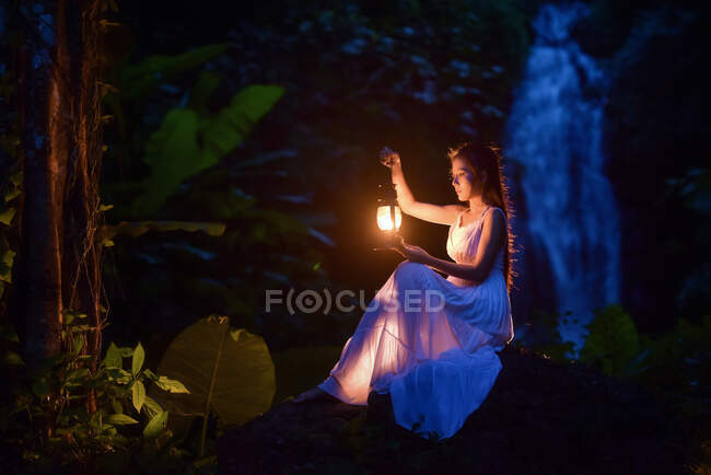 Donna seduta nella foresta con una lanterna in mano, Thailandia — Foto stock
