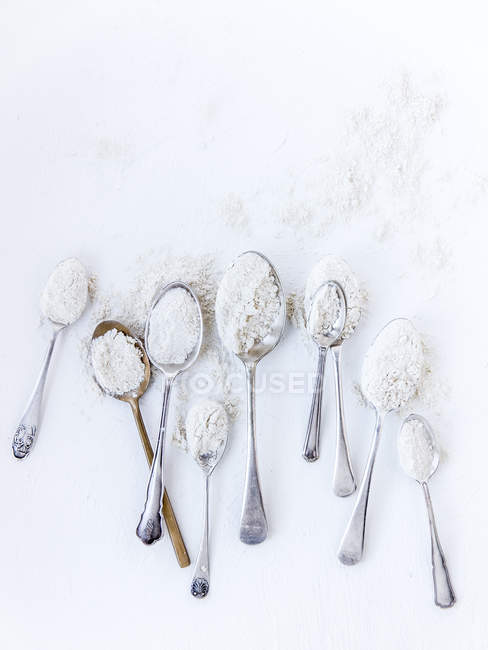 Vista dall'alto di cucchiai con farina su sfondo bianco — Foto stock