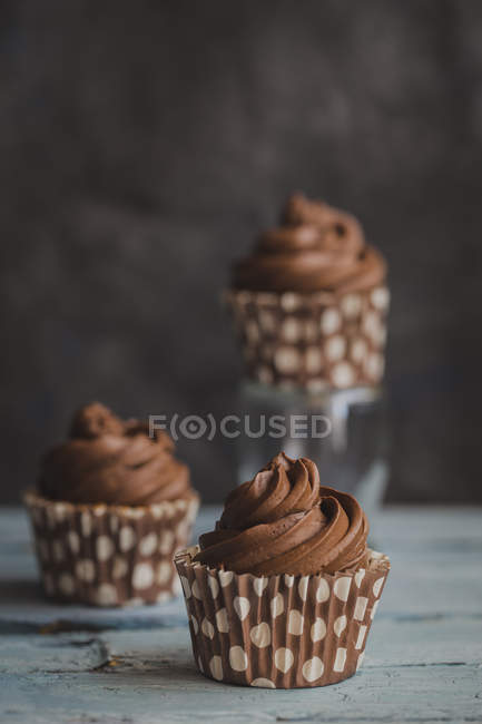 Three chocolate cupcakes on a wood table — Stock Photo